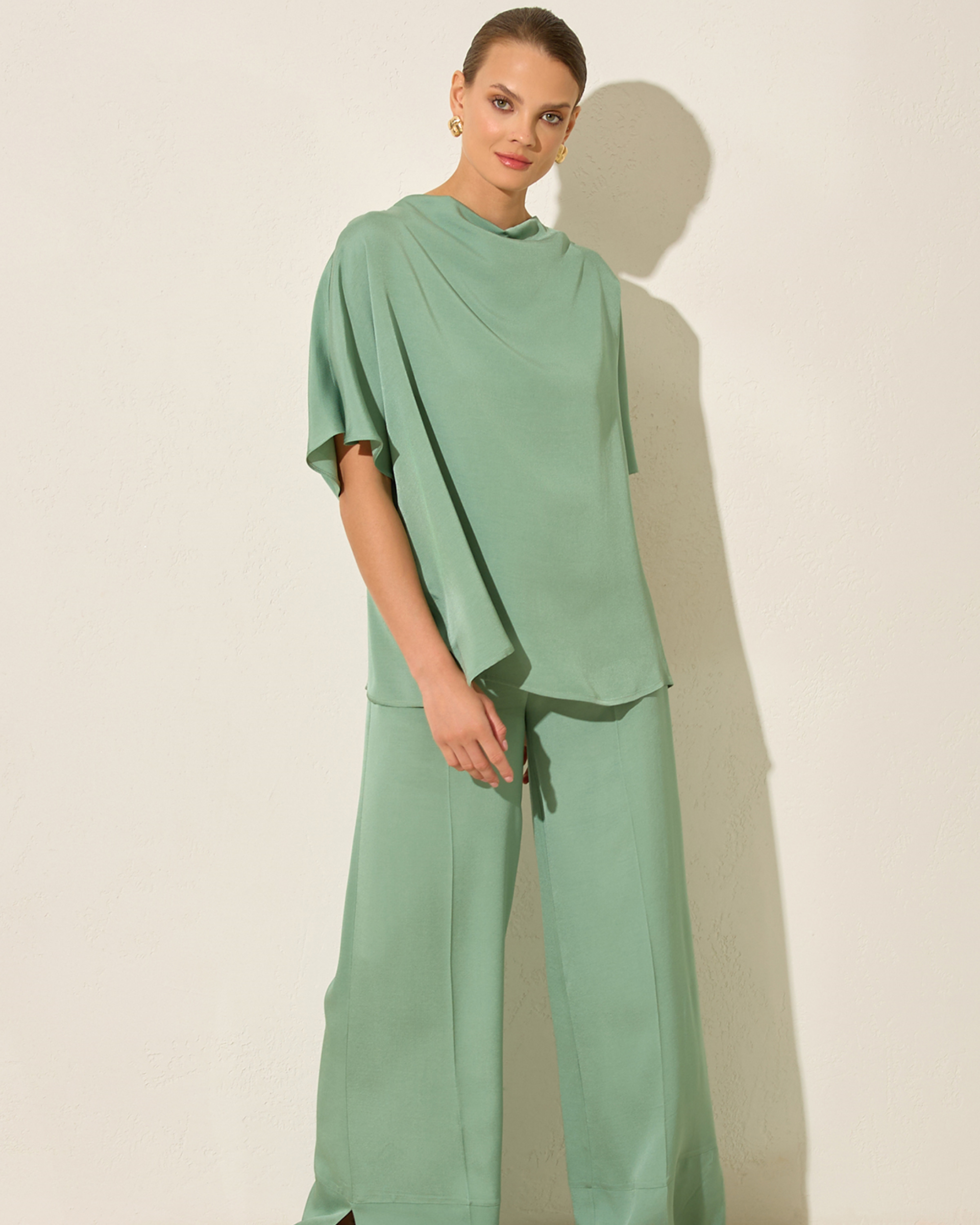 Woman wearing a green outfit against a plain background